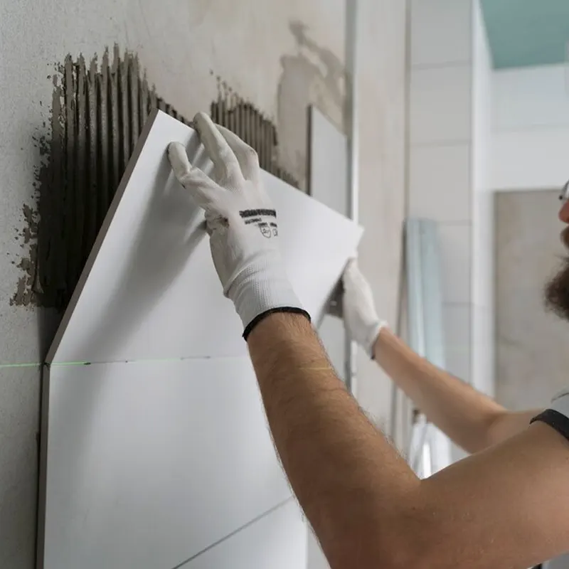 A plumbing professional in Jersey applying waterproof tiles to a bathroom wall to prevent damp and leaks.
