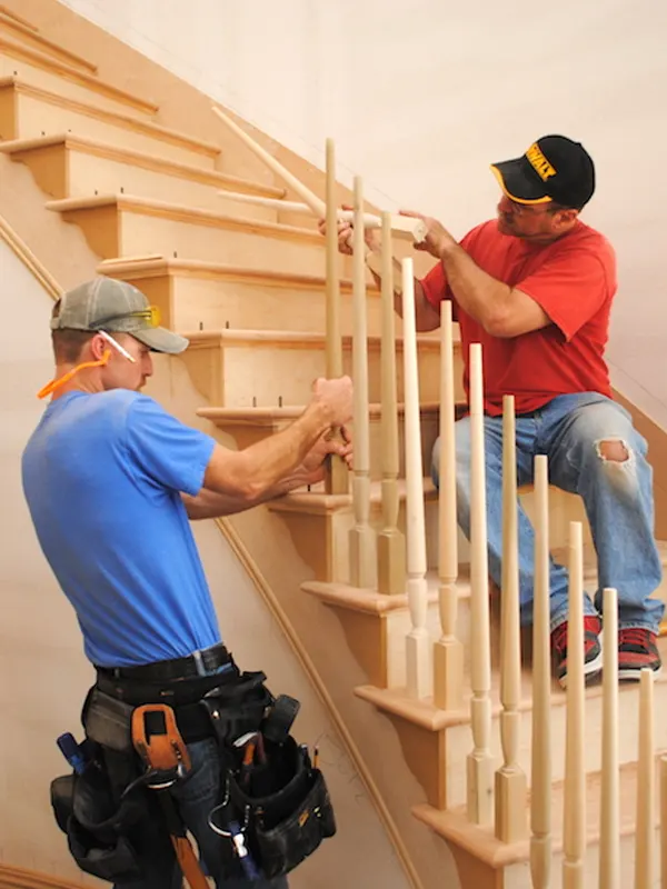 Staircase carpenters installing a custom staircase in a residential building in St. Helier, Jersey.